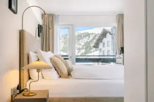 Ein Bett mit Kissen und einer Lampe vor einem Fenster.