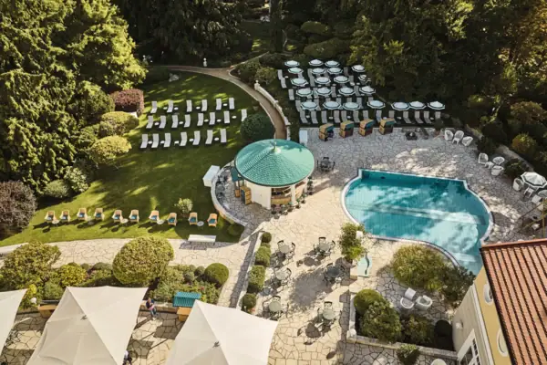 Swimmingpool und Stühle in einem Garten umgeben von Bäumen und Pflanzen.