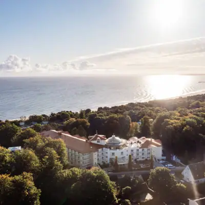 Ein Gebäude am Wasser mit klarem Himmel und Bäumen im Vordergrund.
