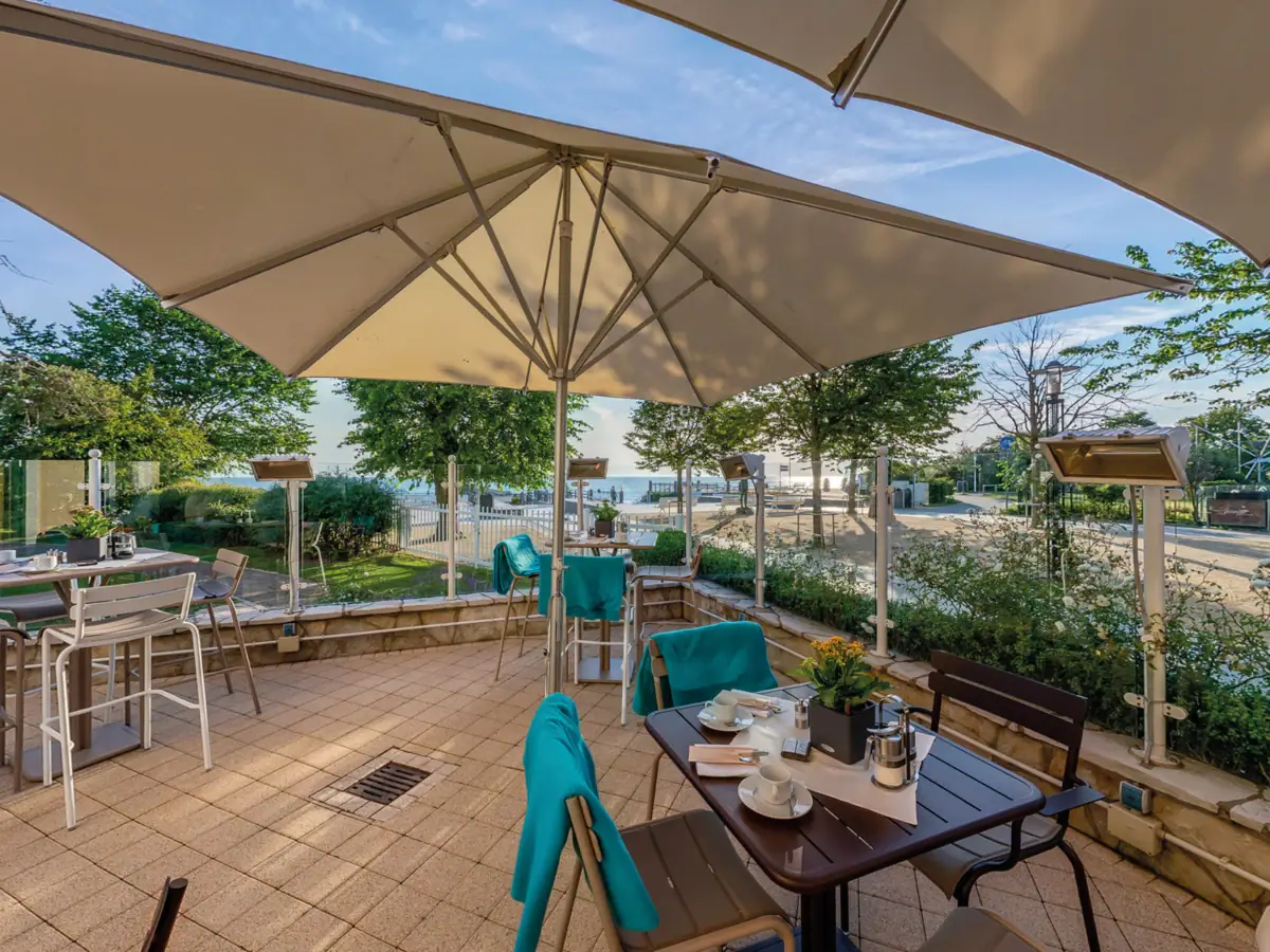 Eine Terrasse mit Tisch, Stühlen und Sonnenschirm.