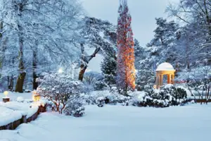 Ein verschneiter Park mit einem Pavillon und Bäumen.