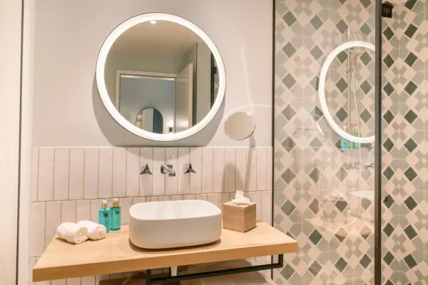 Badezimmer mit rundem Spiegel und Waschbecken