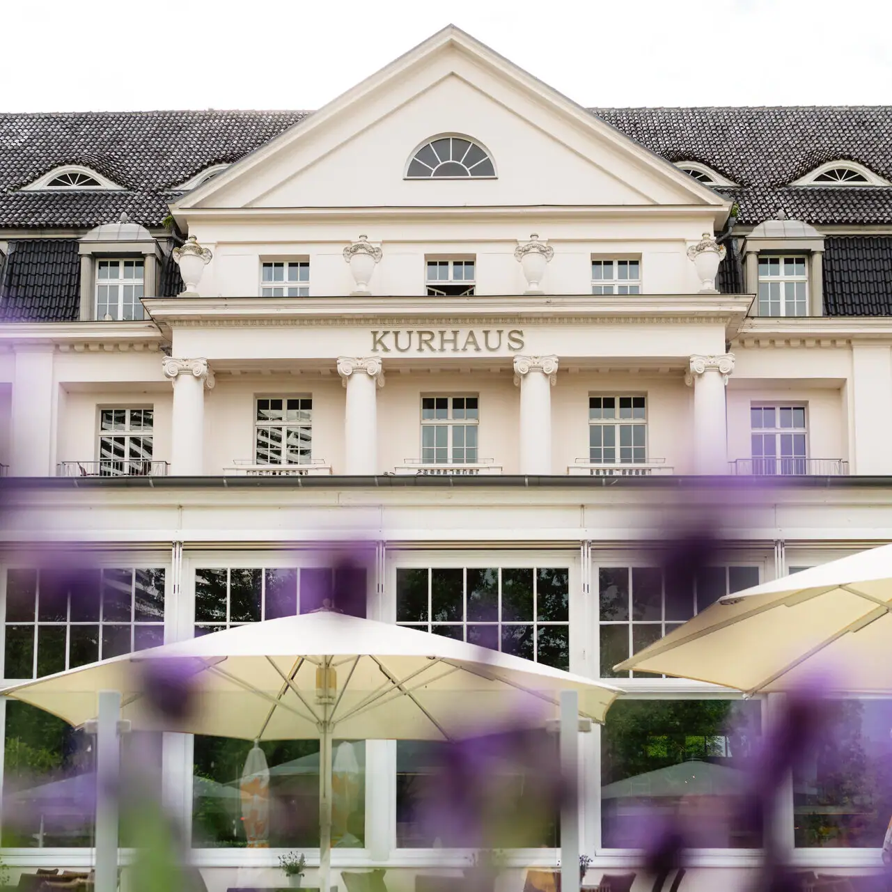 A-ROSA Travemünde Ein Gebäude mit einem großen Fenster und einem großen Sonnenschirm.