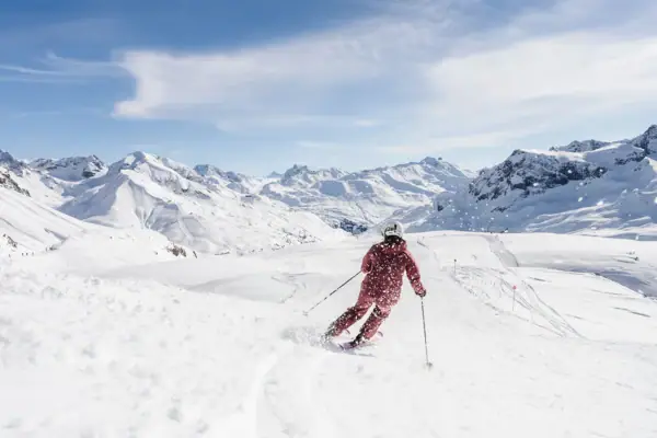 Eine Person fährt auf Skiern einen verschneiten Berg hinunter.