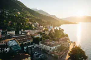 Stadt am Wasser mit Bergen und Bäumen im Hintergrund.