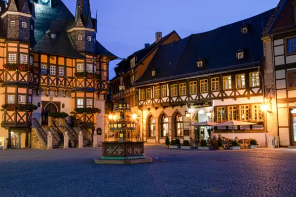 Gothisches Haus Wernigerode Ein Fachwerkgebäude mit einem Brunnen davor.