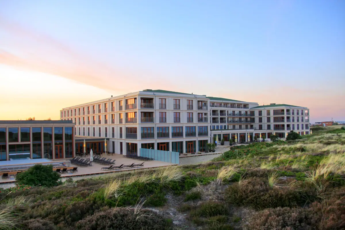 A-ROSA Sylt Ein Gebäude mit Rasen und Stühlen im Freien.