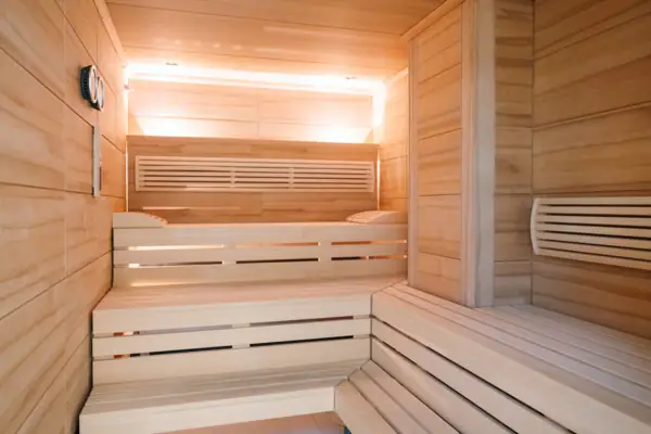 Eine hölzerne Sauna mit Bänken und einer Lampe im Hintergrund.