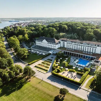 Großes Gebäude mit Pool, umgeben von Bäumen.