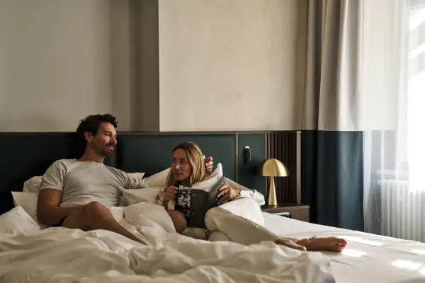 Ein Mann und eine Frau liegen auf einem Bett in einem gemütlichen Zimmer.
