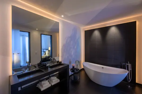 Zimmer Badezimmer mit Badewanne und Waschbecken, ausgestattet mit modernen Armaturen und einem Spiegel.