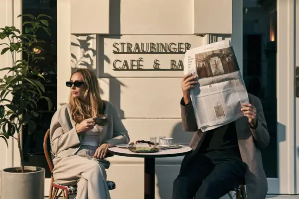 Ein Mann und eine Frau sitzen an einem Tisch und lesen eine Zeitung.