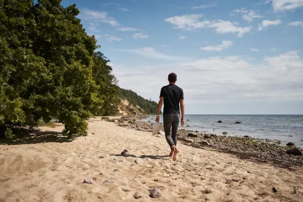 Ein Mann spaziert am Strand entlang.