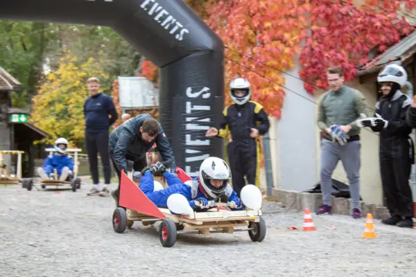 Eine Gruppe von Personen mit Helmen auf einem kleinen Holzhandwagen.