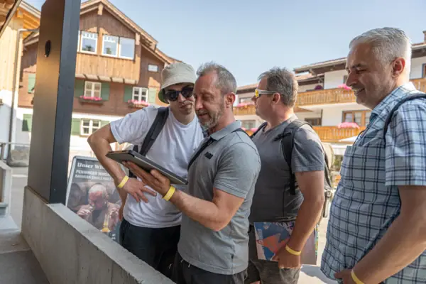 Eine Gruppe von Männern steht im Freien und betrachtet ein Tablet.