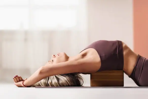Yogapose Eine Frau liegt auf einem Block.