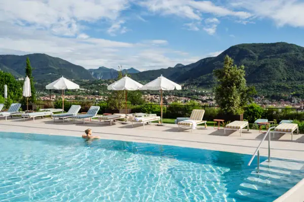 Person im Pool mit Sonnenschirmen und Liegestühlen im Hintergrund.