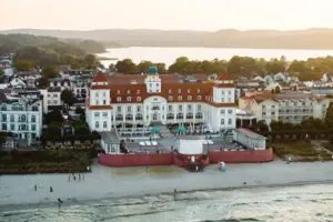 Kurhaus Binz Großes Gebäude mit Strand und Wasser im Hintergrund