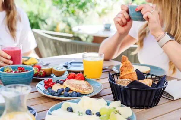 Eine Frau hält eine Tasse Kaffee und einen Teller mit Essen.