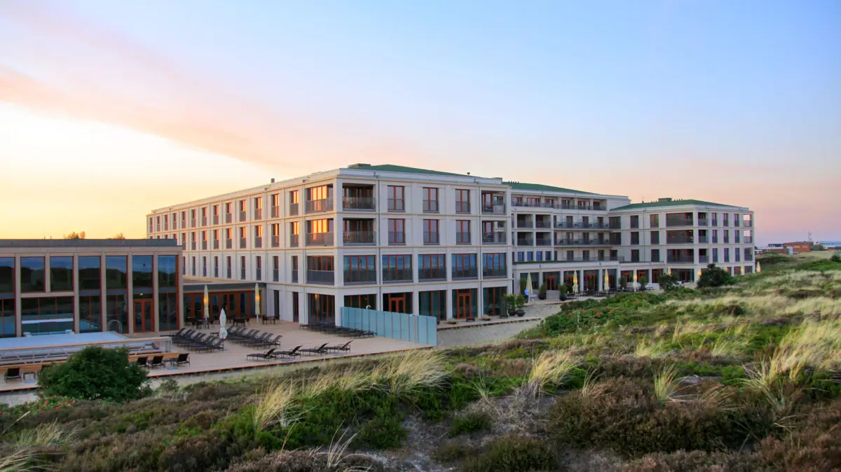 Gebäude mit Rasen und Stühlen im Freien bei Sonnenaufgang.