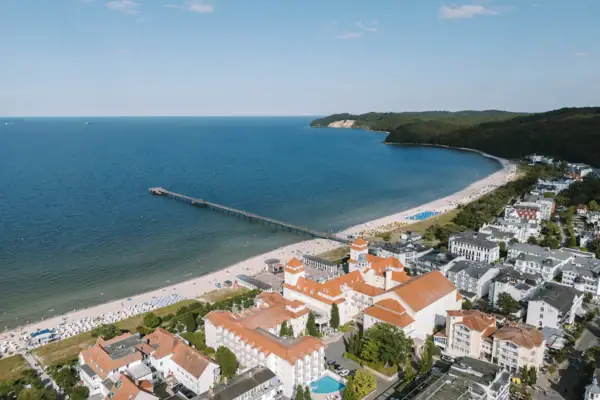 Strand mit Gebäuden und einem Pier im Vordergrund.