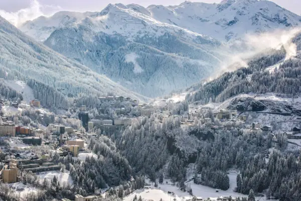 Verschneiter Berg mit Gebäuden und Bäumen.