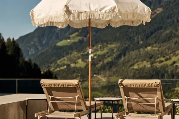 Weißer Sonnenschirm und Stühle auf einem Deck