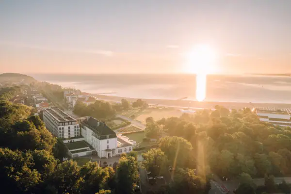 Großes Gebäude neben einem Gewässer bei Sonnenaufgang.