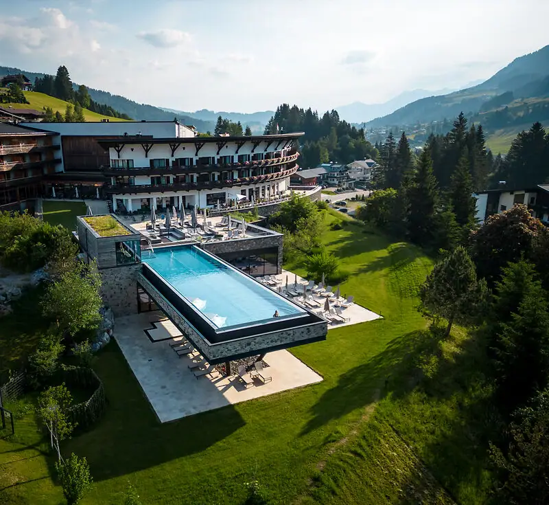 A-ROSA Ifen Hotel Kleinwalsertal Außenpool eines Hotels mit Blick auf Bäume und Himmel.