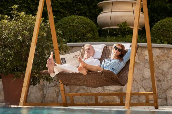 Ein Mann und eine Frau liegen in einer Hängematte am Pool.