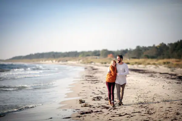 Ein Mann und eine Frau spazieren am Strand.