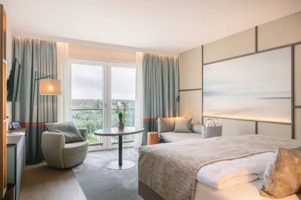 Ein Hotelzimmer mit einem Bett, einemSchreibtisch und einem gemütlichen Sessel.