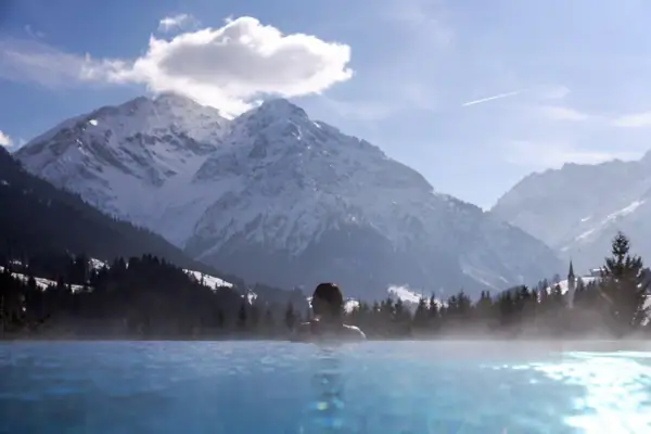 Eine Person in einem Pool mit Bergen im Hintergrund.
