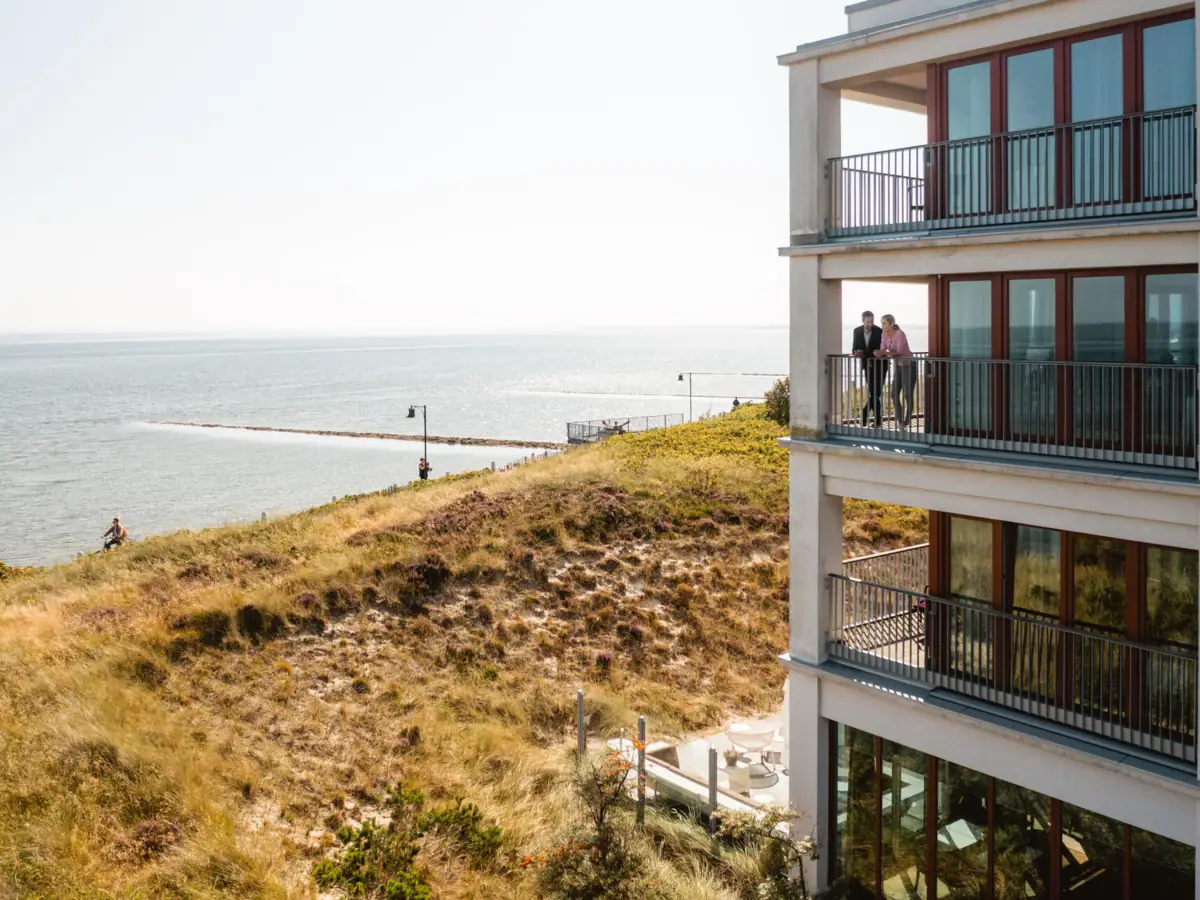 Ein Paar steht auf einem Balkon mit Blick auf die Nordsee vor Sylt.