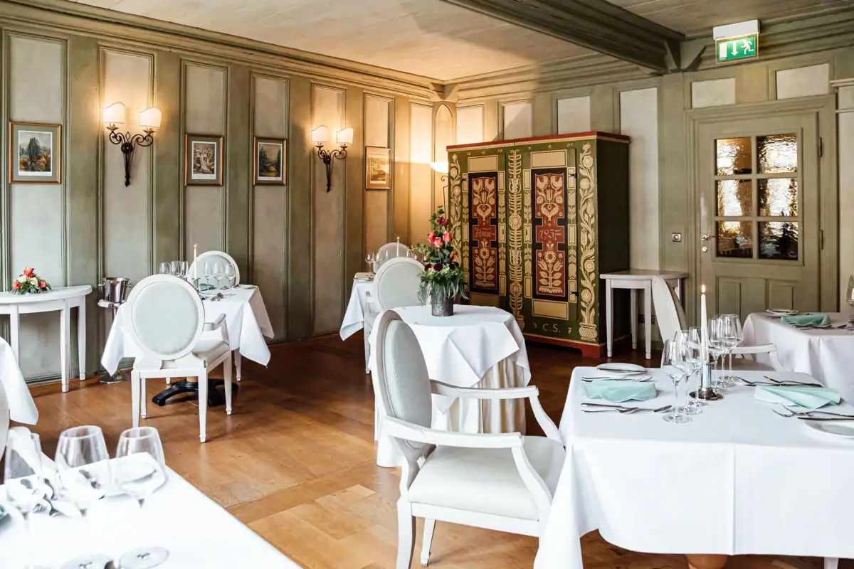 Ein Raum mit Tischen und Stühlen, eingerichtet für ein gehobenes Essen.