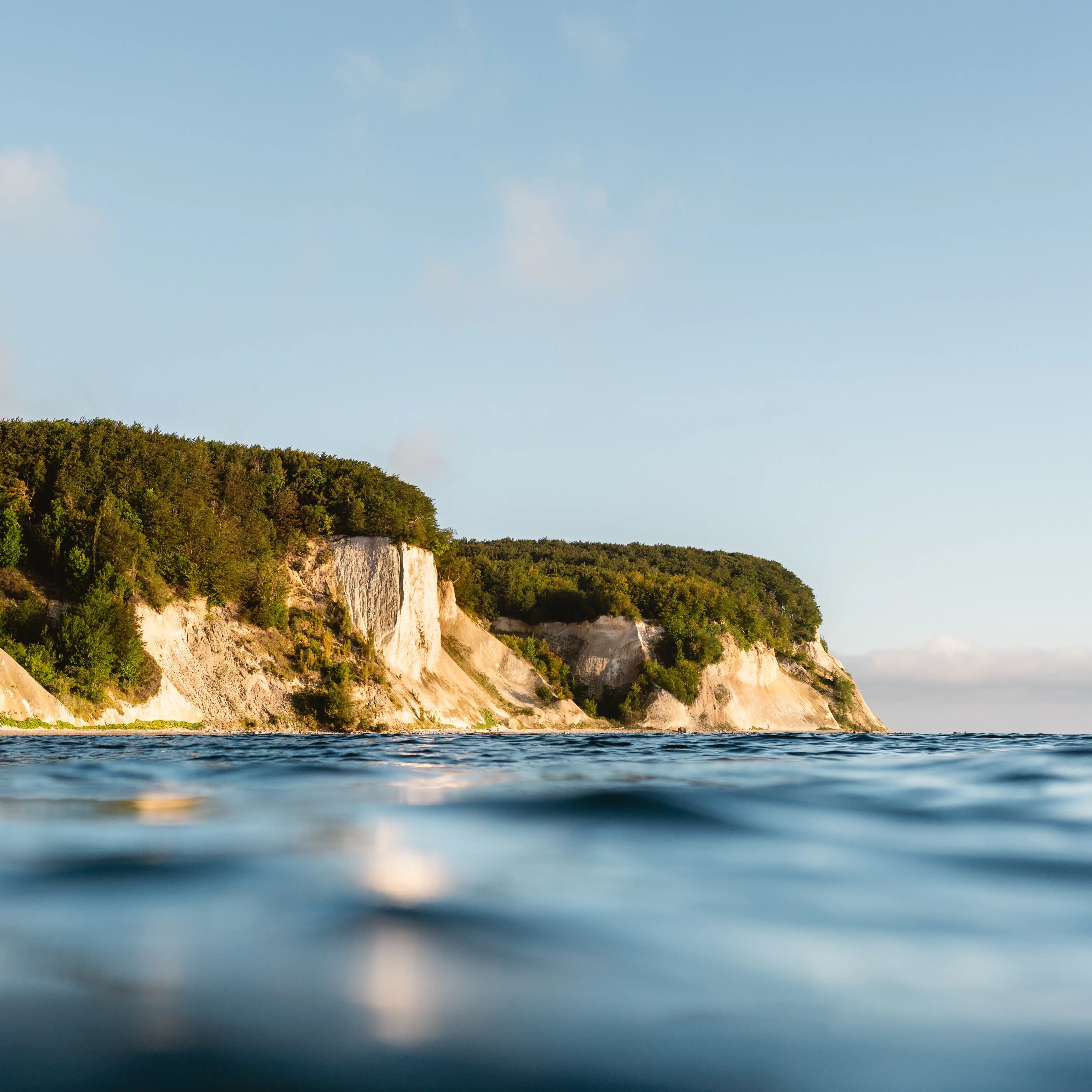 Ein Gewässer mit einer Klippe und Bäumen.