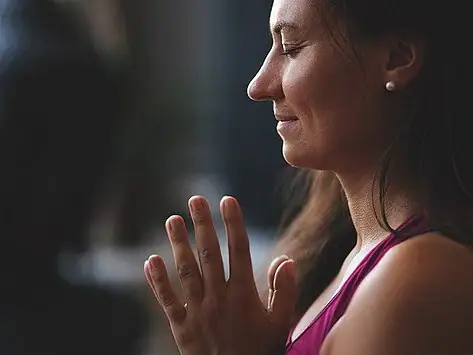 Eine Frau mit zusammengelegten Händen in Yoga-Position..