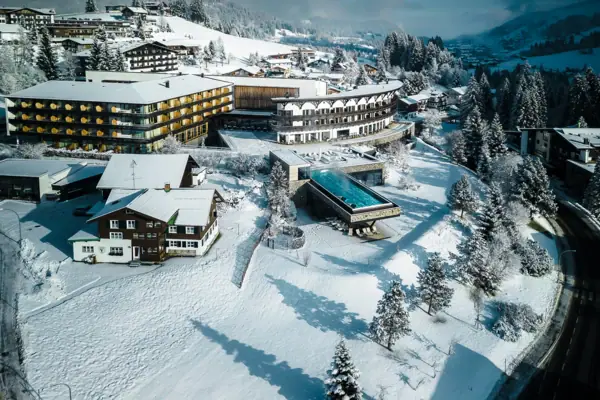 A-ROSA Ifen Hotel Kleinwalsertal Verschneite Landschaft mit Häusern und Bäumen.
