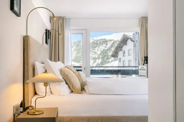 Ein Bett mit Kissen und einer Lampe vor einem Fenster.