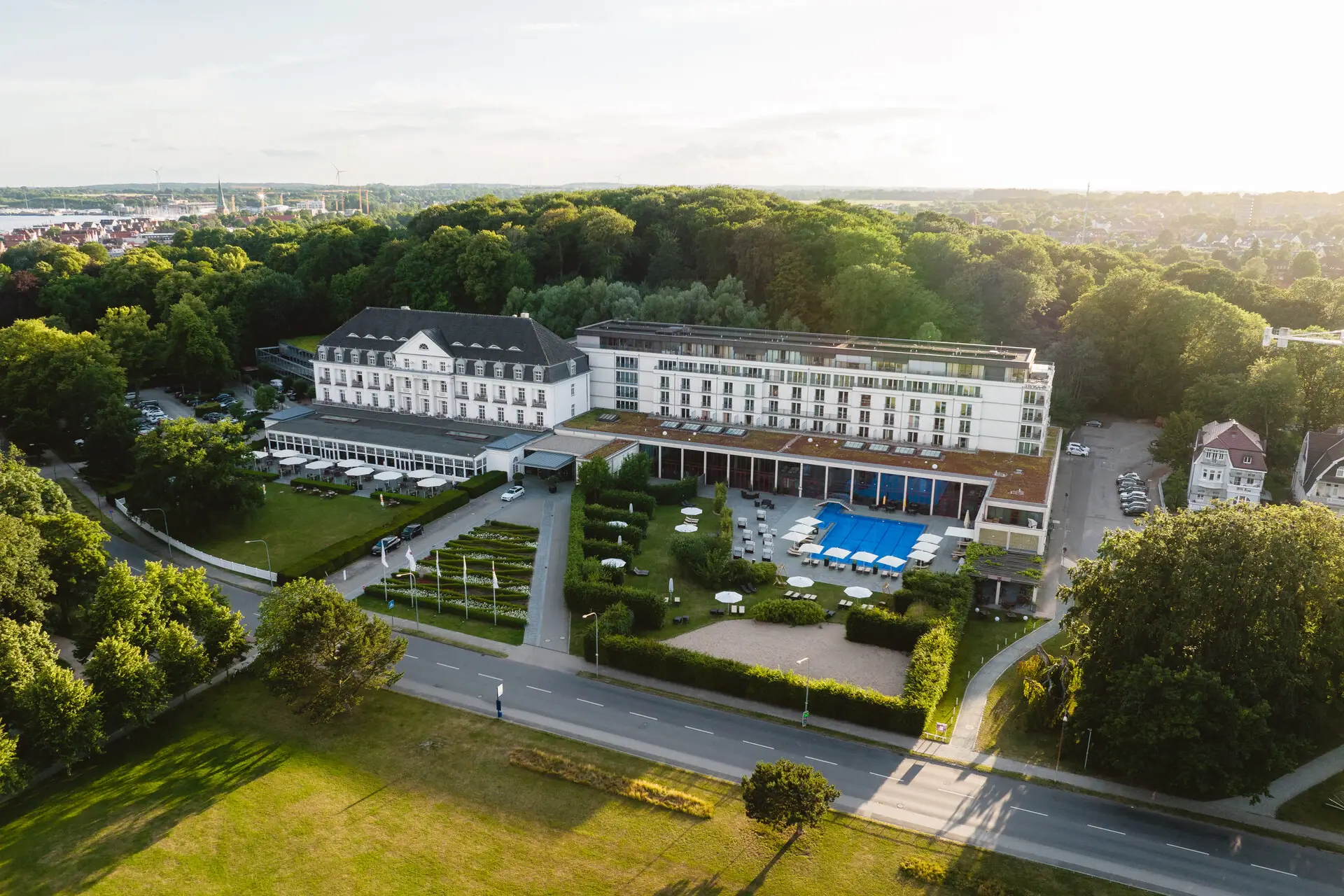 Ein großes weißes Gebäude mit einem Pool und Bäumen.