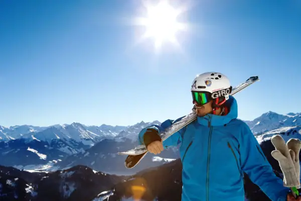 Ein Mann hält einen Ski und einen Helm.