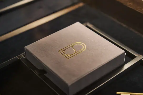 Graue Schachtel mit goldenem Logo darauf