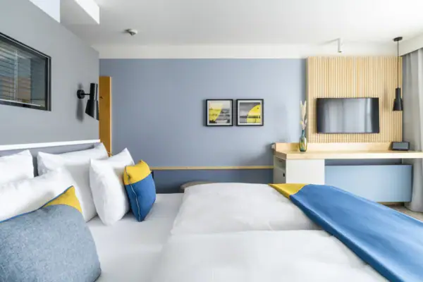 Ein modernes Hotelzimmer mit einem Bett, einem Schreibtisch und einem Fernseher.