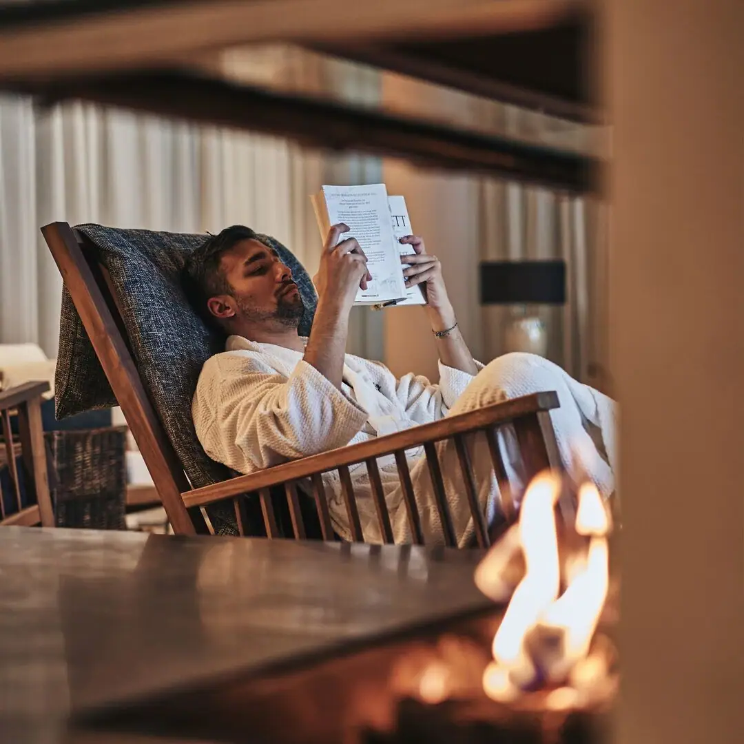 Ein Mann im weißen Bademantel liest ein Buch.