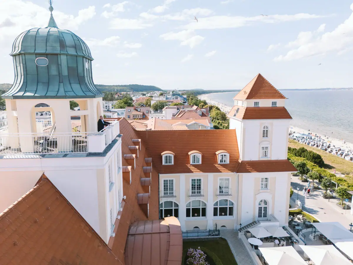 Das Kurhaus Binz mit Glockenturm und Strand im Vordergrund.
