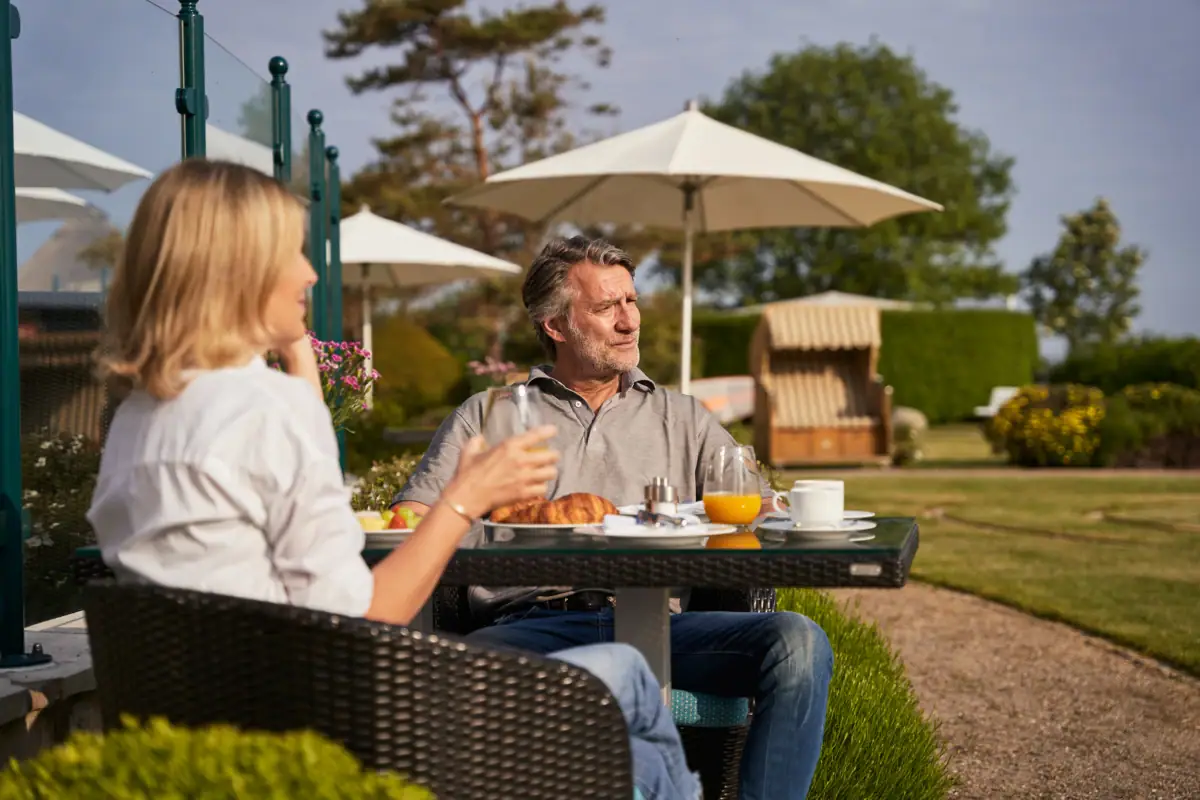 Ein Mann und eine Frau sitzen an einem Tisch im Freien.