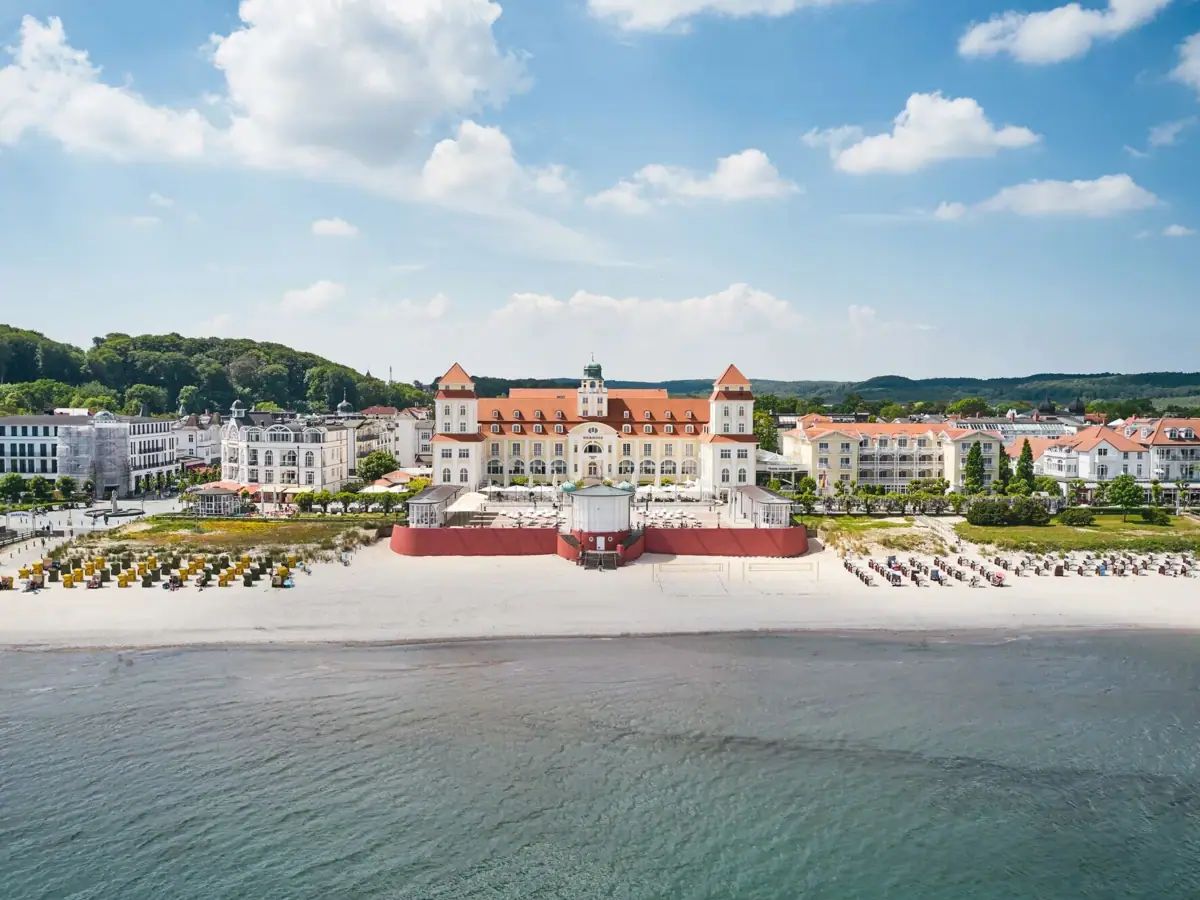 Das Kurhaus Binz mit Glockenturm und Strand im Vordergrund.