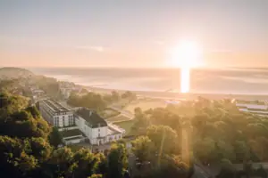 Stadtansicht mit Bäumen und einem Gewässer bei Sonnenaufgang.