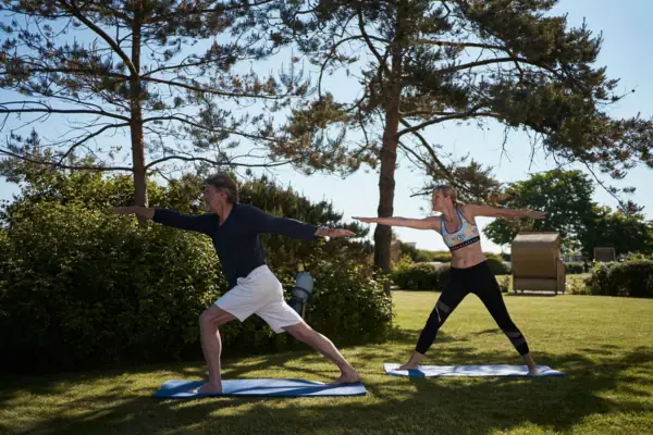 Ein Mann und eine Frau machen Yoga auf dem Rasen.