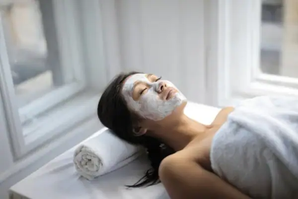 PURE Gesichtsbehandlung Eine Frau liegt mit einer weißen Maske auf dem Gesicht.